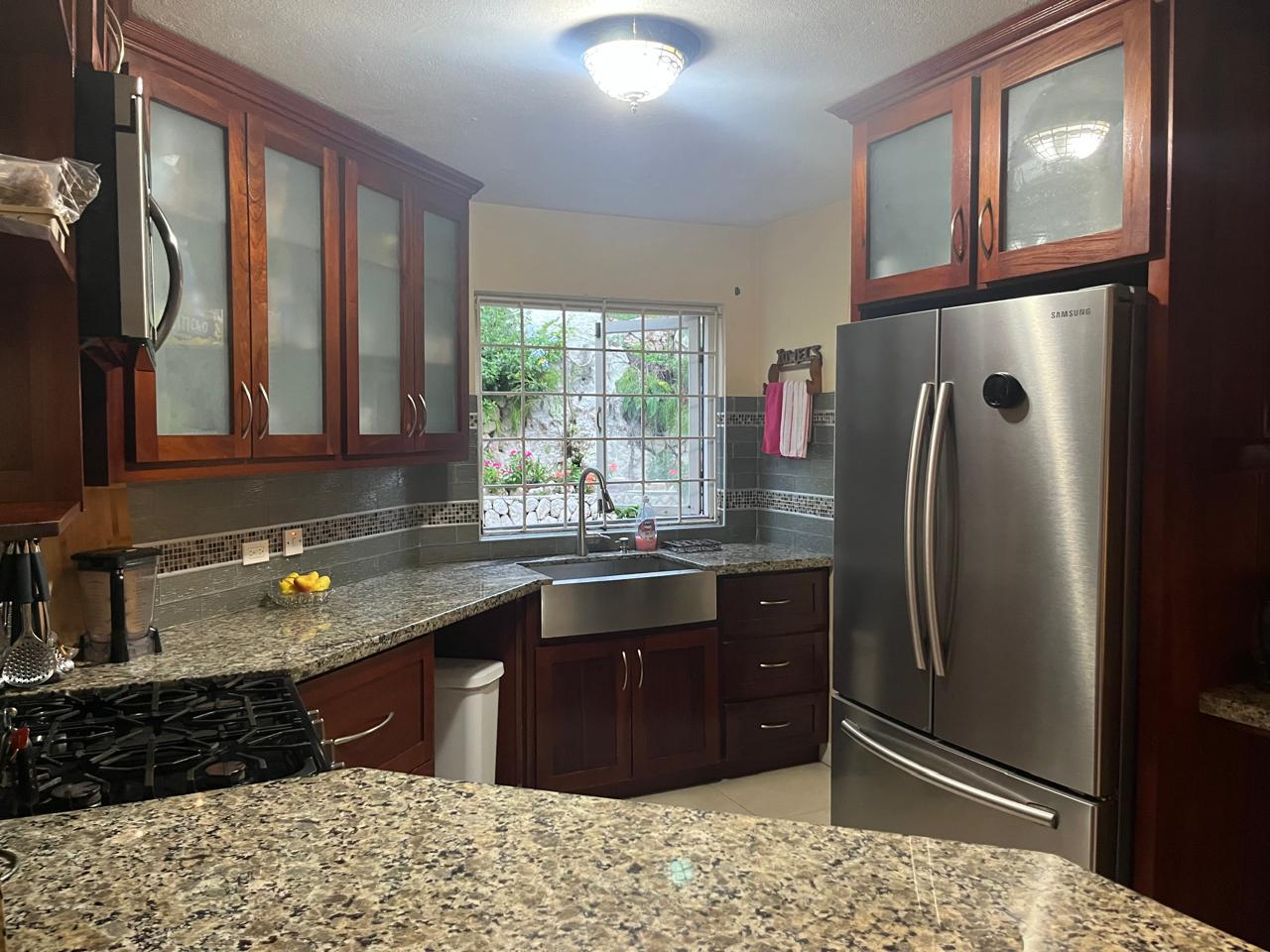 The same kitchen fully cleared, sanitised and polished with empty sink and gleaming counters after Luxe Clean JA