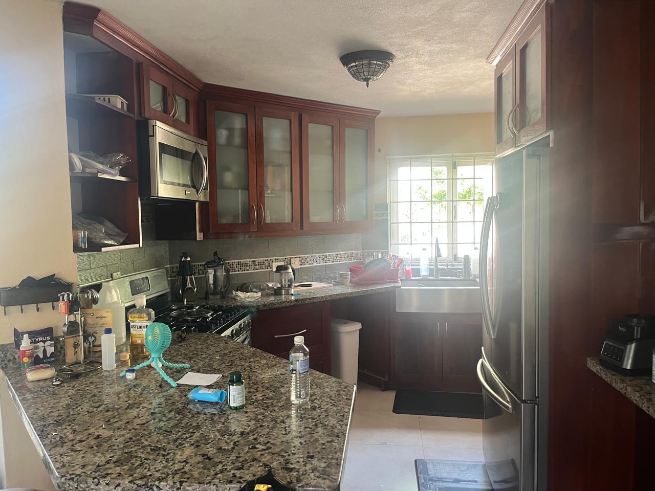 Cluttered kitchen with dishes in the sink and items scattered across the granite counter before cleaning