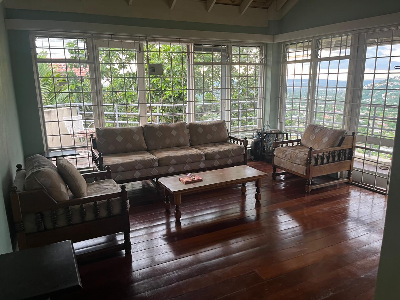 The same living room tidied and reset with neatly arranged pillows and clear surfaces after Luxe Clean JA